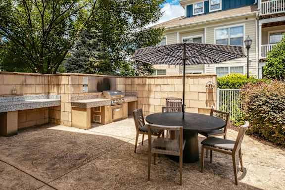 A patio with a table and chairs and a black umbrella.