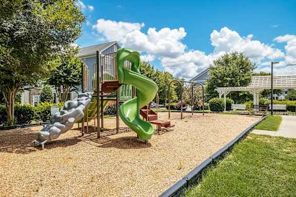A playground with a green slide and a red and brown structure.