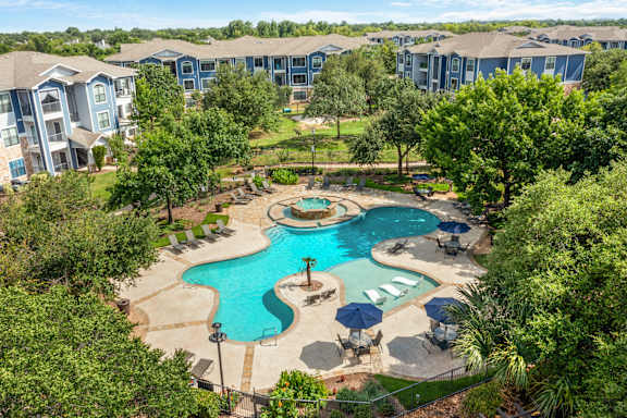 A large swimming pool surrounded by trees and chairs.