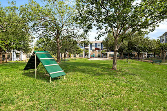 A playground with a green slide and a green bench.