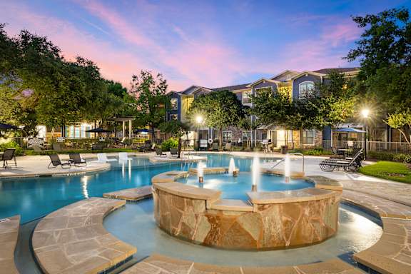 A large outdoor swimming pool with a hot tub in the middle.