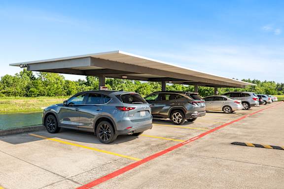A row of cars are parked under a canopy.
