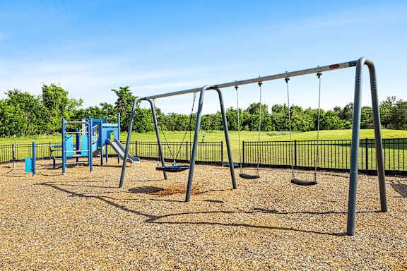 A playground with a swing set and a blue slide.