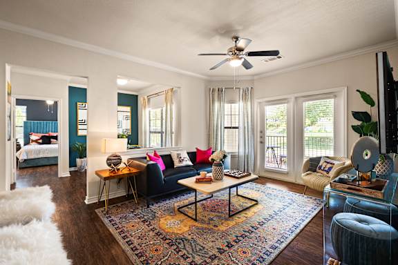 A living room with a black couch and a rug.