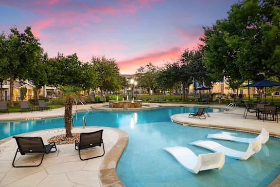A pool with a waterfall and a tree in the middle.