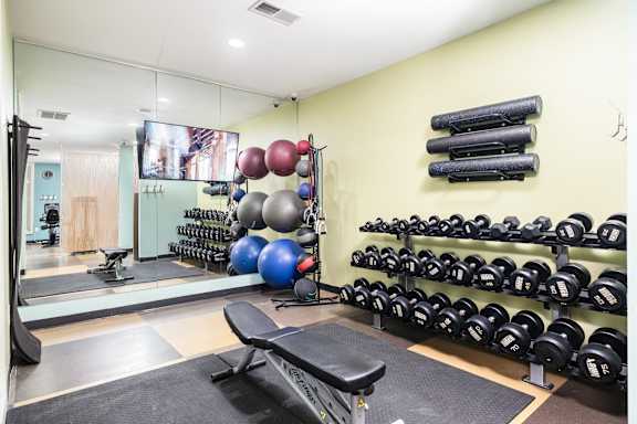 A gym with a bench, weights, and a mirror.