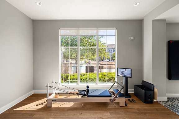 A room with a wooden floor and a row of windows.
