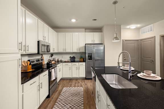 A modern kitchen with white cabinets and black countertops.
