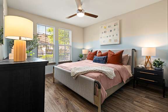 A bedroom with a bed, nightstand, and a ceiling fan.