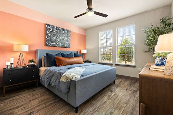 A bedroom with a bed, nightstands, and a ceiling fan.