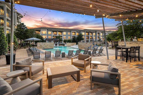 A patio with a table and chairs overlooking a pool.