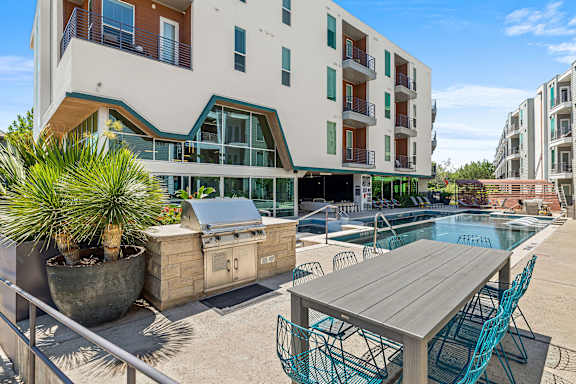 A modern apartment complex with a pool and outdoor furniture.