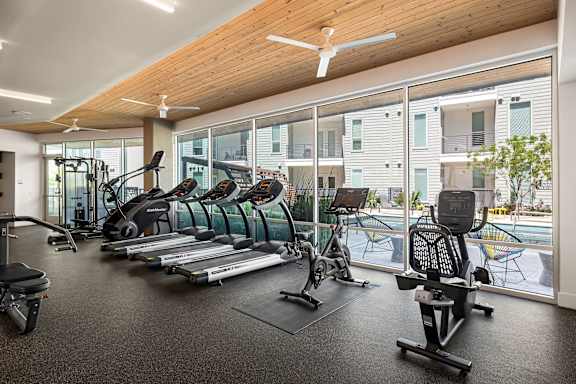 A gym with a variety of equipment including treadmills, elliptical machines, and weights.