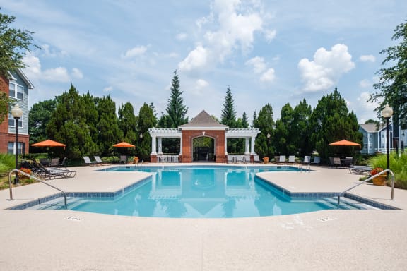 a swimming pool with a gazebo and umbrellas near a resort