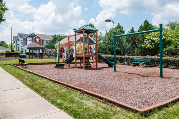 a playground with a swing set and slides in a park