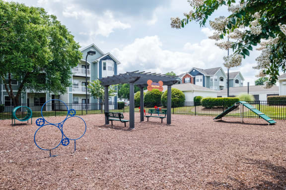 a playground with benches and a swing set in front of houses