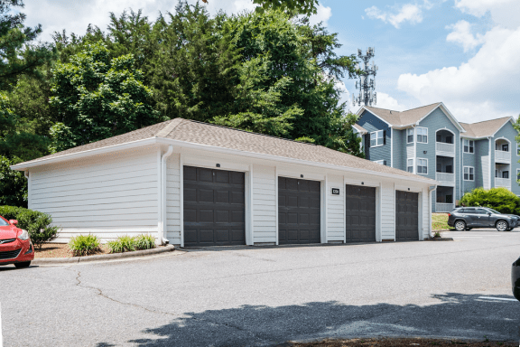 a garage with two black garage doors in front of an apartment building