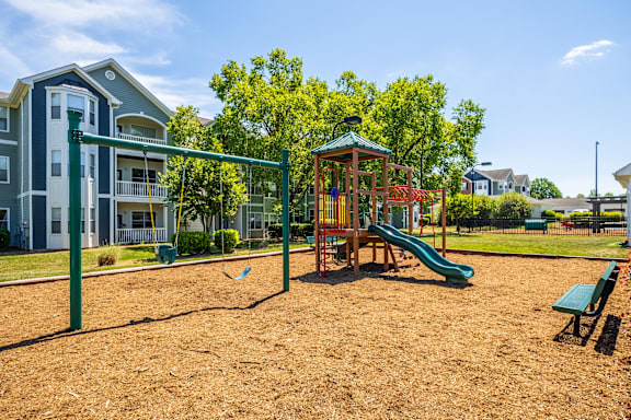 A playground with a green slide and a red and yellow play structure.