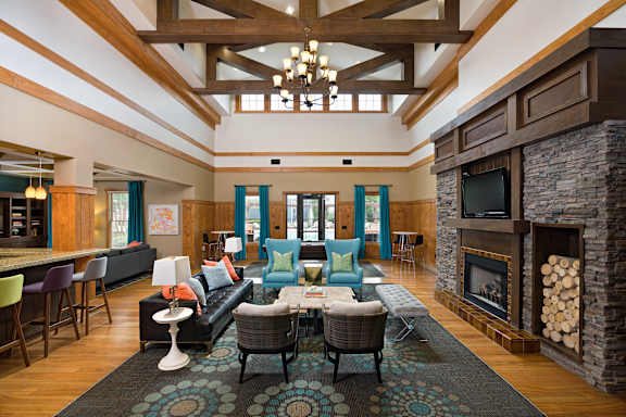 A living room with a stone fireplace and a large rug.