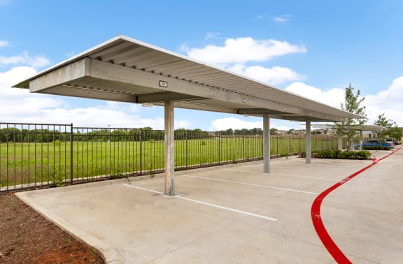 a covered parking lot with a green field in the background