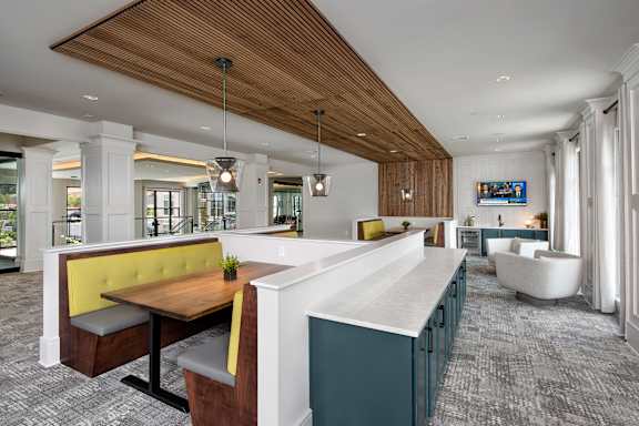 A modern restaurant interior with a wooden ceiling and grey carpet.