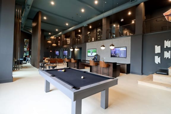 a pool table in a room with a lot of televisions