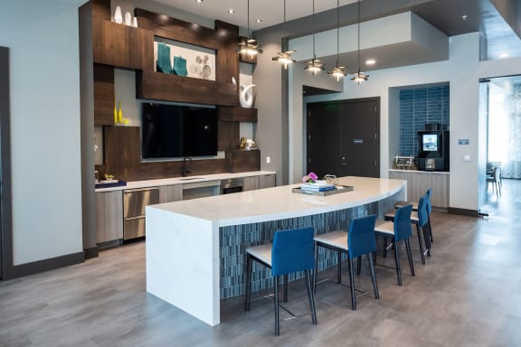 a modern kitchen with a large island and blue chairs around it