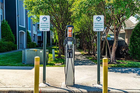 Two signs that say electric vehicle charging only stand next to a charging station.