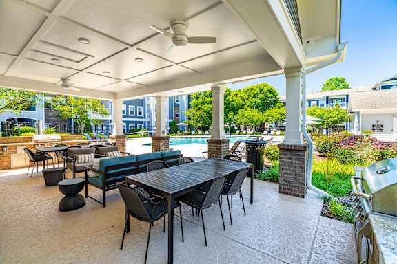 A patio with a table and chairs is covered by a roof.