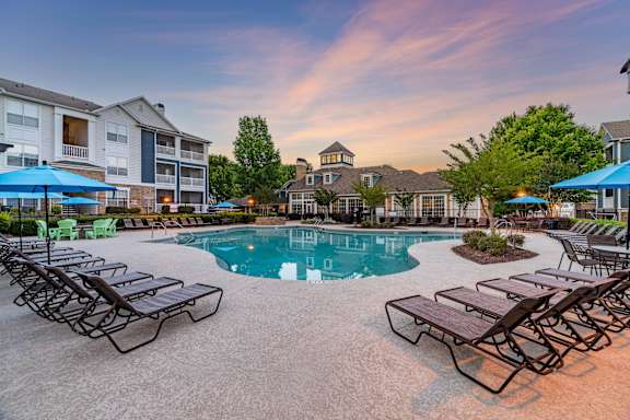 A pool surrounded by lounge chairs and umbrellas.