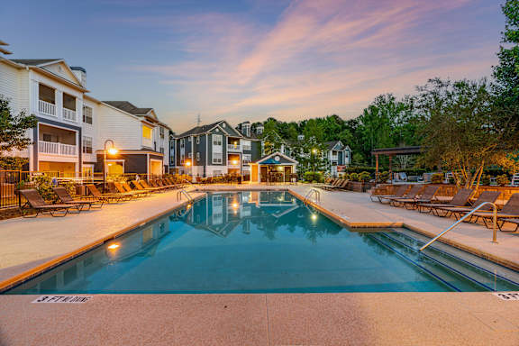 A swimming pool surrounded by lounge chairs and buildings.