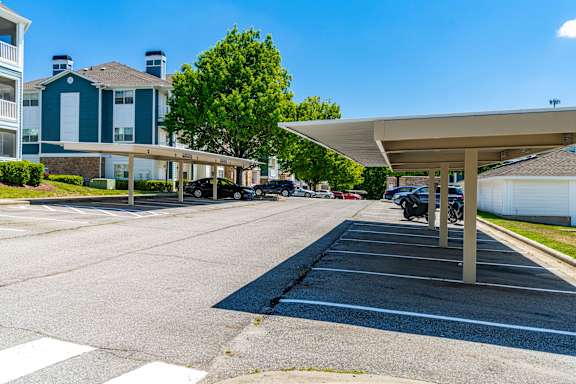 A parking lot with a white canopy and cars parked under it.