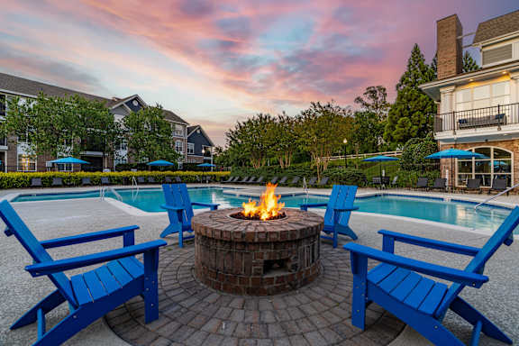 A fire pit surrounded by blue chairs in a backyard.