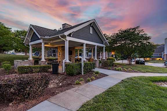 A house with a front porch and a sidewalk leading to it.