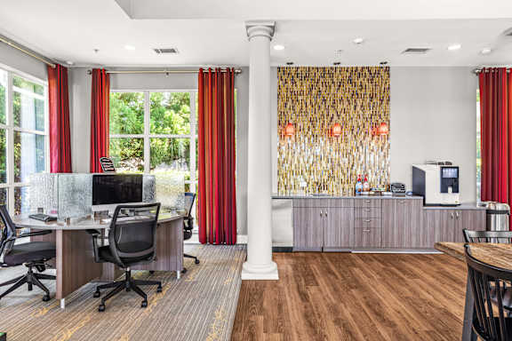 A room with a desk, chairs, and a window with red curtains.