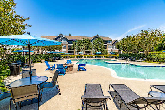 A pool area with chairs and umbrellas.
