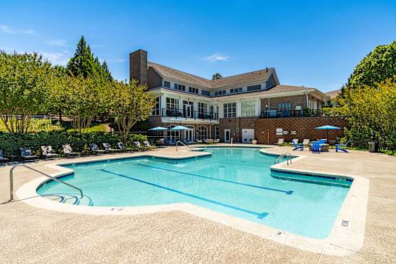 A large swimming pool in front of a building surrounded by trees.