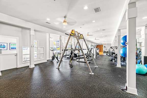 A gym with a variety of equipment including a treadmill, exercise balls, and weights.