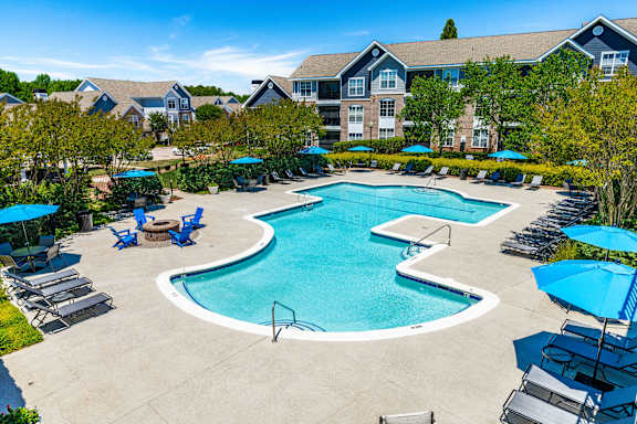 A large swimming pool surrounded by lounge chairs and umbrellas.