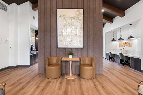 A room with a brown table and chairs with a large picture hanging on the wall.