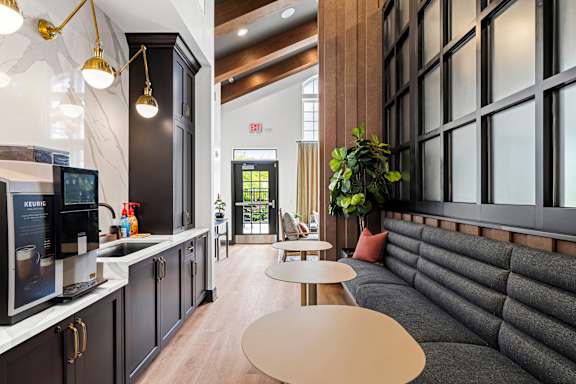 A modern kitchen with a black countertop and a grey couch.