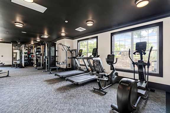 A gym with a variety of equipment including treadmills, weights, and exercise machines.