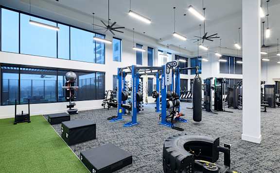 A gym with a variety of equipment including weights and a green artificial turf area.