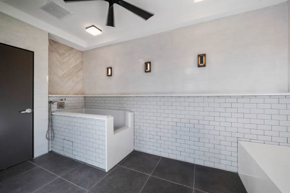 a bathroom with white tiles and a tub and a sink