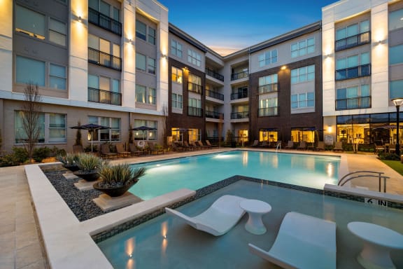 a swimming pool in front of an apartment building at night