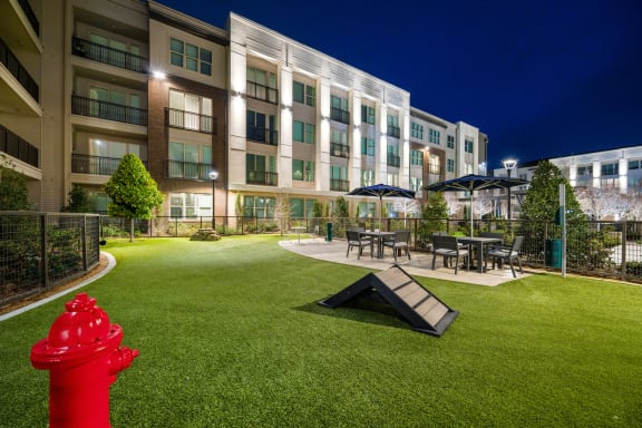 a red fire hydrant sitting on a green lawn in front of an apartment building