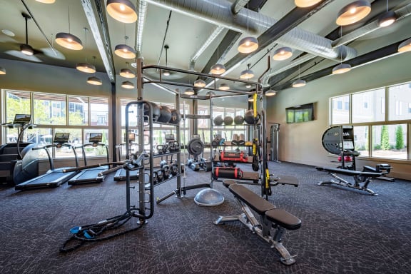 a spacious fitness center with cardio equipment and windows