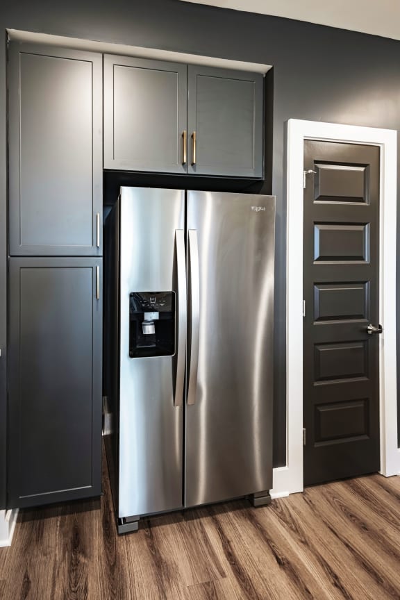 a stainless steel refrigerator in a kitchen with dark gray cabinets