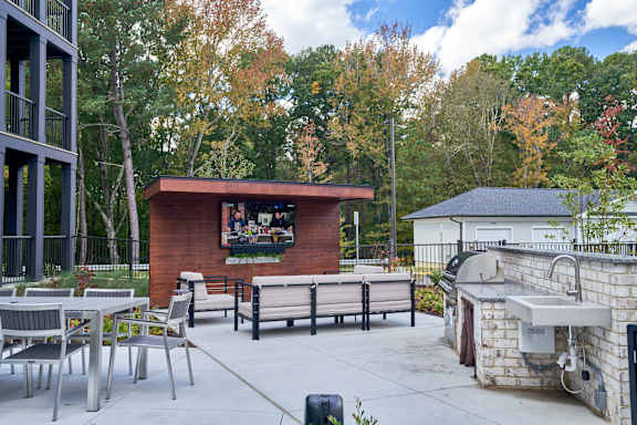 A patio with a couch, chairs, and a TV.