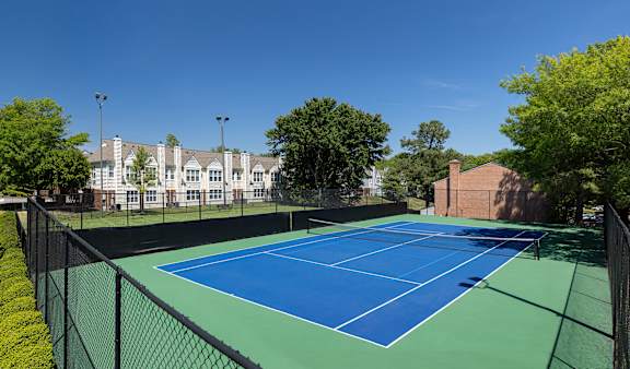 A tennis court surrounded by a black fence.